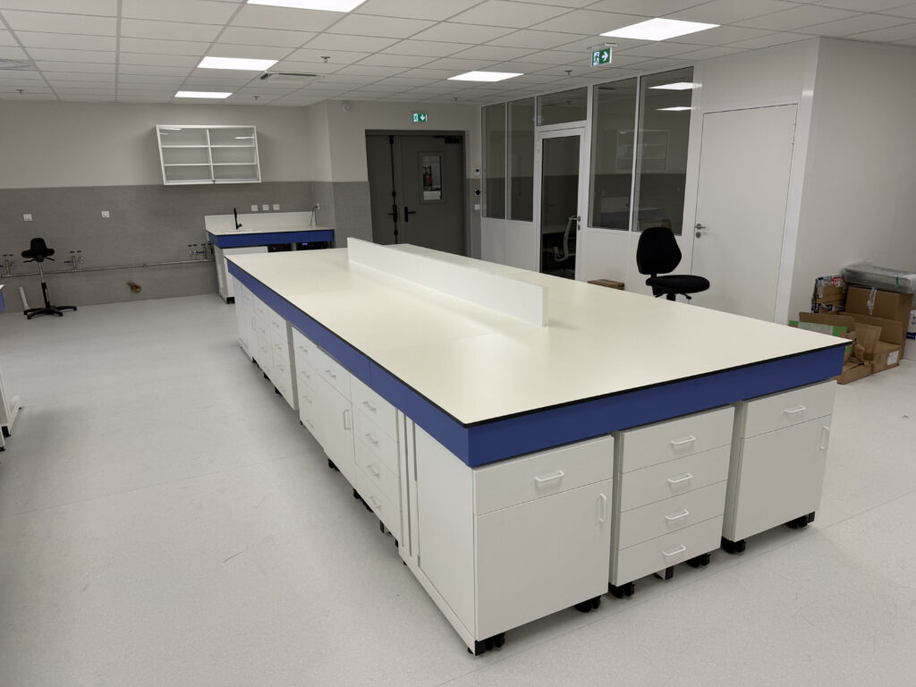 Détail d’une paillasse centrale de laboratoire avec tiroirs et plan de travail en Trespa